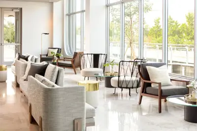 a living room with couches and tables and windows at Kimpton - Hotel Palomar South Beach by IHG in Miami Beach