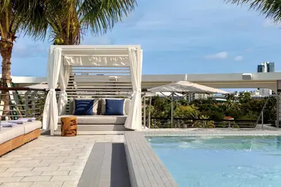 a pool with a gazebo and a couch next to a pool at Kimpton - Hotel Palomar South Beach by IHG in Miami Beach