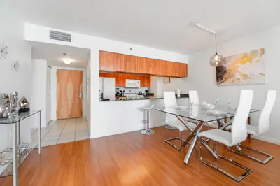 a kitchen and dining room with a glass table and white chairs at Fabulous apartment in Brickell in Miami