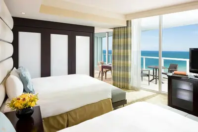 a hotel room with two beds and a balcony at Fontainebleau Miami Beach in Miami Beach