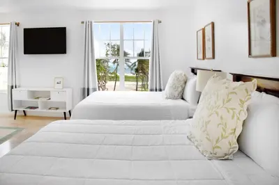 a white bedroom with two beds and a television at Beach Park Hotel in Miami Beach