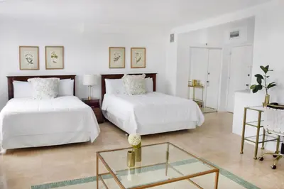 two beds in a white room with a glass table at Beach Park Hotel in Miami Beach