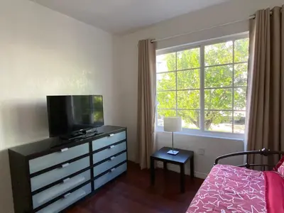 a bedroom with a dresser with a tv and a window at Harding Boutique Apartments in Miami Beach
