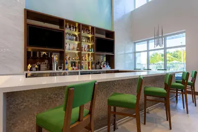 a bar with green chairs in a room at Wyndham Garden Miami International Airport in Miami