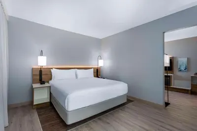 a bedroom with a white bed and a mirror at Wyndham Garden Miami International Airport in Miami