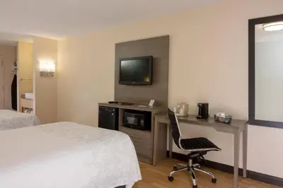 a hotel room with a bed and a desk with a television at Red Roof PLUS Miami Airport in Miami