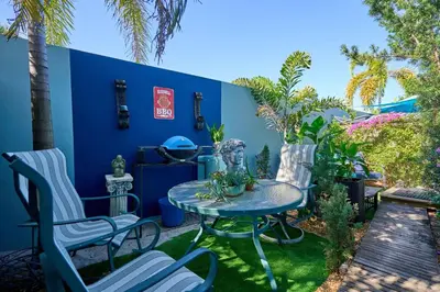 a patio with a table and chairs and a blue wall at Blue Bell Apartment Hotel in Fort Lauderdale
