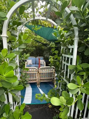 a pergola with a couch in a garden at Blue Bell Apartment Hotel in Fort Lauderdale