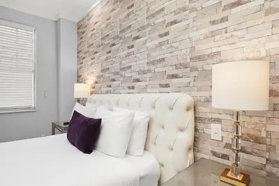 a bedroom with a white bed and a brick wall at Shelley Hotel in Miami Beach