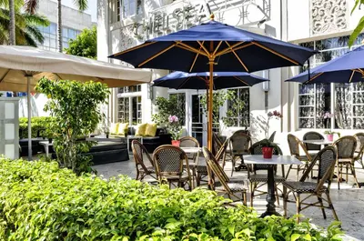 an outdoor patio with tables and chairs and umbrellas at Hotel Chelsea in Miami Beach