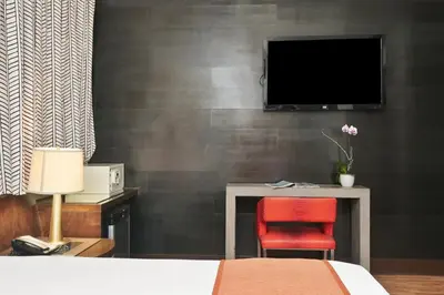 a bedroom with a tv and a red chair at Hotel Chelsea in Miami Beach