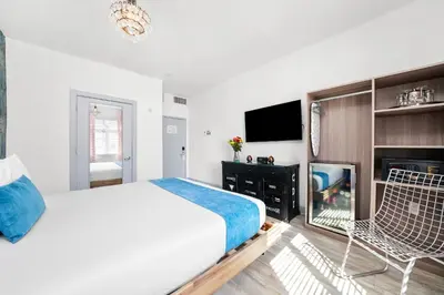 a white bedroom with a bed and a tv at Whitelaw Hotel in Miami Beach