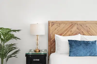 a bedroom with a bed with a wooden headboard and a lamp at Whitelaw Hotel in Miami Beach