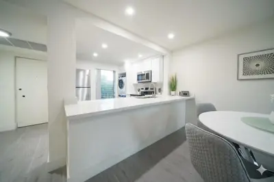 a white kitchen with a counter and a table at Designer River View Apartments in Fort Lauderdale