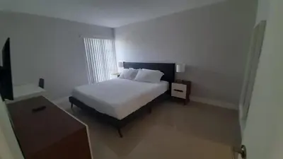 a bedroom with a white bed and a night stand at Designer River View Apartments in Fort Lauderdale