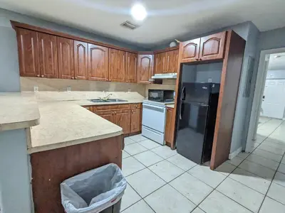 a kitchen with wooden cabinets and a black refrigerator at MiLuSol in Miami