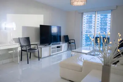 a white living room with a tv and a couch at Cozy and Luminous Apartment - 00388 in Miami Beach