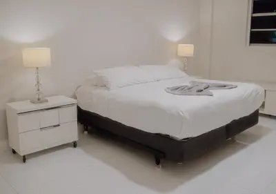 a white bedroom with a bed and a night stand at Cozy and Luminous Apartment - 00388 in Miami Beach