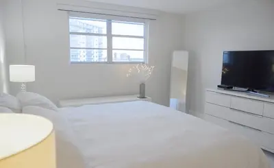a white living room with a white couch and a tv at Cozy and Luminous Apartment - 00388 in Miami Beach