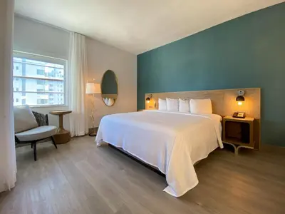 a bedroom with a large white bed and a chair at Marseilles Beachfront Hotel in Miami Beach
