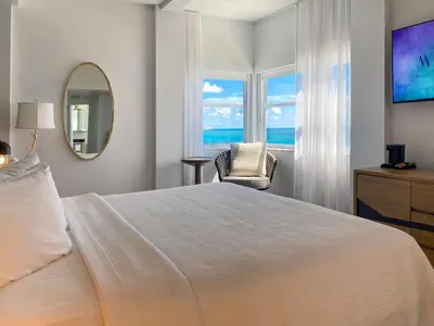 a bedroom with a bed and a mirror and a chair at Marseilles Beachfront Hotel in Miami Beach