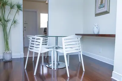 a glass table and four white chairs in a room at Dorchester Hotel & Suites in Miami Beach