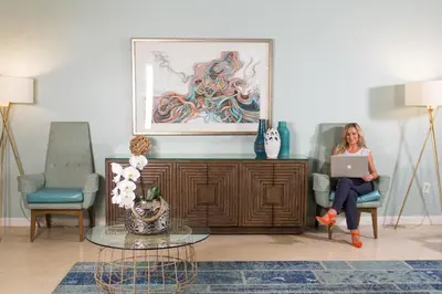 a woman sitting in a chair with a laptop in a living room at Dorchester Hotel & Suites in Miami Beach