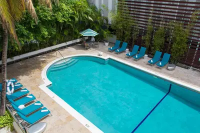a swimming pool with chairs and an umbrella at Dorchester Hotel & Suites in Miami Beach