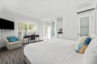 a white bedroom with a large bed and a table at The Pillars Hotel & Club in Fort Lauderdale