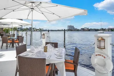 a white table with chairs and an umbrella on a boat at The Pillars Hotel & Club in Fort Lauderdale
