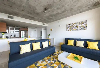 a living room with a blue couch and yellow pillows at Modern 1 Bedroom Midtown Miami with FREE Parking in Miami