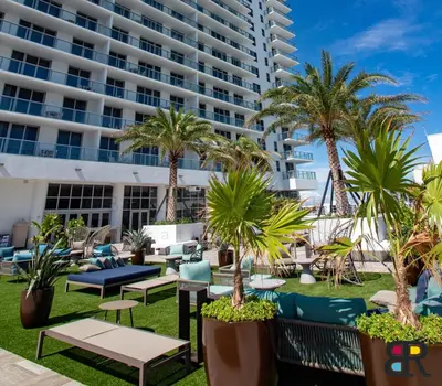 a hotel patio with chairs and palm trees and a large building at HYDE Beach House Apartments in Hollywood