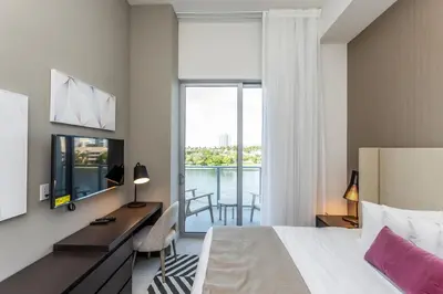 a hotel room with a bed and a desk and a window at Amazing Apartments at H Beach House in Hollywood