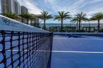 a tennis net on a tennis court with palm trees at Amazing Apartments at H Beach House in Hollywood