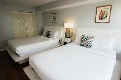 two beds in a hotel room with white sheets at Alexander 1209 Beachfront condo with 2 pools , beach access, sauna, stores in Miami Beach