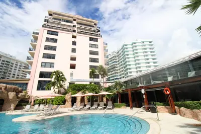 a swimming pool with chairs and a tall building at Alexander 1209 Beachfront condo with 2 pools , beach access, sauna, stores in Miami Beach