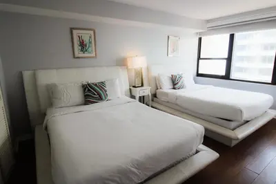 a white bedroom with two beds and a window at Alexander 1209 Beachfront condo with 2 pools , beach access, sauna, stores in Miami Beach