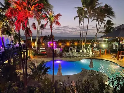 a view of a pool with palm trees at night at Alexander 511 Beachfront condo with 2 pools, direct beach access, sauna, tikki bar in Miami Beach