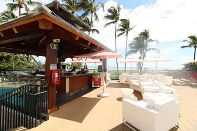 a bar with white chairs and umbrellas on a deck at Alexander 511 Beachfront condo with 2 pools, direct beach access, sauna, tikki bar in Miami Beach