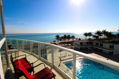 a balcony with chairs and a swimming pool and the ocean at Castle M16 Oceanview Loft with Beach access, Pool, Tennis and Free Parking! in Miami Beach