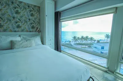 a bedroom with a bed and a large window with the ocean at Castle M16 Oceanview Loft with Beach access, Pool, Tennis and Free Parking! in Miami Beach