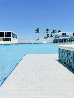 a swimming pool with blue water and palm trees at Castle 828 Oceanfront view with balcony, pool, tennis, beach access and free parking! in Miami Beach