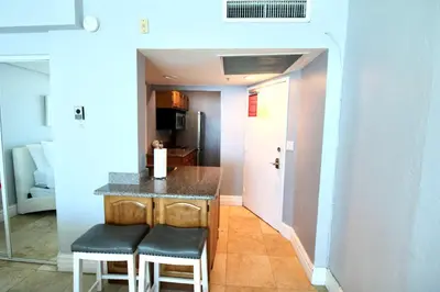 a kitchen with a counter and two stools at Castle 828 Oceanfront view with balcony, pool, tennis, beach access and free parking! in Miami Beach