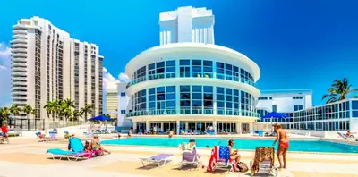 a building with people sitting in chairs in front of a pool at Castle 922 in Miami Beach