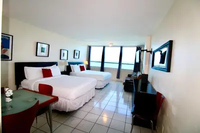 a hotel room with two beds and a table and a room at Castle 1033 in Miami Beach