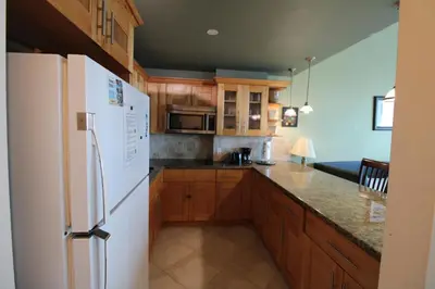 a kitchen with a white refrigerator and wooden cabinets at Castle B17 Contemporary Condo with Pool, Beach Access and Free Parking in Miami Beach