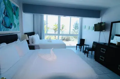 a hotel room with two beds and a television at Castle Th16 Beachfront Townhouse with private patio, direct beach access, pool, tennis & free parking! in Miami Beach