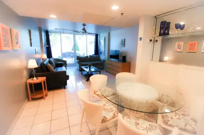 a living room with a glass table and white chairs at Castle Th16 Beachfront Townhouse with private patio, direct beach access, pool, tennis & free parking! in Miami Beach