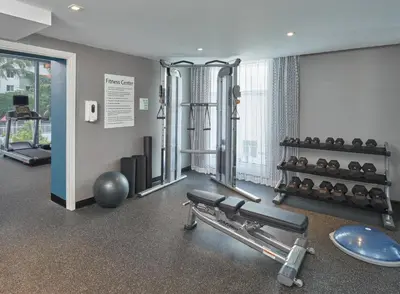 a room with a gym with a bench and weights at DoubleTree by Hilton Miami North I-95 in Miami