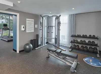 a room with a gym with a bench and weights at DoubleTree by Hilton Miami North I-95 in Miami
